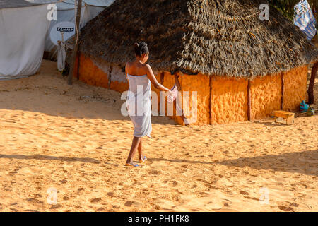 Deserto LAMPOUL, SENEGAL - Apr 23, 2017: Non identificato donna senegalese cammina con una borsa vicino la baracca in un deserto Lampoul, bellissimo paesaggio luogo Foto Stock
