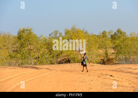 Deserto LAMPOUL, SENEGAL - Apr 23, 2017: Non identificato donna senegalese in abiti colorati e velo passeggiate con un sacchetto in un deserto Lampoul, bella Foto Stock