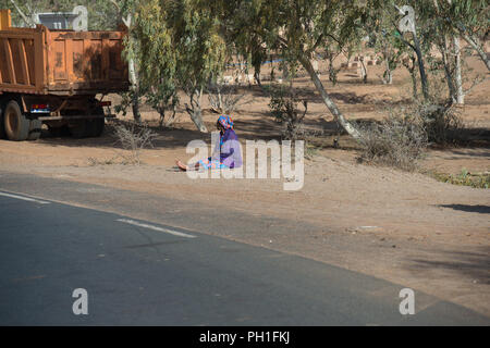 Deserto LAMPOUL, SENEGAL - Apr 23, 2017: Non identificato donna senegalese si siede per terra accanto alla strada vicino al carrello in un villaggio vicino al Lampoul Foto Stock
