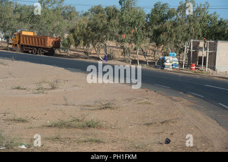 Deserto LAMPOUL, SENEGAL - Apr 23, 2017: Non identificato donna senegalese si siede per terra accanto alla strada vicino al carrello in un villaggio vicino al Lampoul Foto Stock