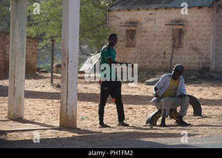 Deserto LAMPOUL, SENEGAL - Apr 23, 2017: Non identificato uomo senegalese si siede sul pneumatico auto accanto alla strada in un villaggio vicino al deserto Lampoul Foto Stock