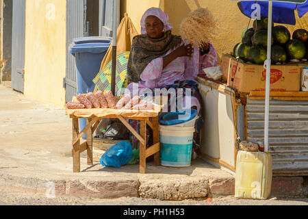 SAINT LOUIS, SENEGAL - Apr 24, 2017: Non identificato donna senegalese si siede sotto un ombrellone e vende merci sulla strada di Saint Louis, uno dei bigges Foto Stock