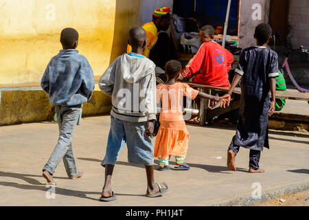 SAINT LOUIS, SENEGAL - Apr 24, 2017: Unidentified senegalesi poco tre ragazzi e una ragazza camminare a fianco della strada al mercato locale di Saint Louis, Se Foto Stock