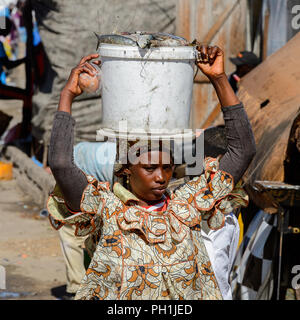 SAINT LOUIS, SENEGAL - Apr 24, 2017: Non identificato donna senegalese porta un secchio con il pesce sulla sua testa al mercato locale di Saint Louis, Senegal Foto Stock