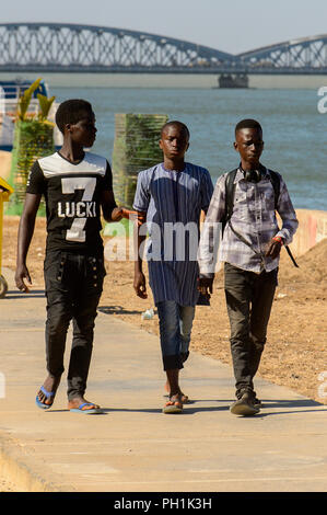 SAINT LOUIS, SENEGAL - Apr 24, 2017: Senegalesi non identificato tre ragazzi a piedi lungo la strada sulle rive dell'oceano a Saint Louis, uno dei bigge Foto Stock