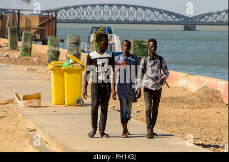 SAINT LOUIS, SENEGAL - Apr 24, 2017: Senegalesi non identificato tre ragazzi a piedi lungo la strada sulle rive dell'oceano a Saint Louis, uno dei bigge Foto Stock