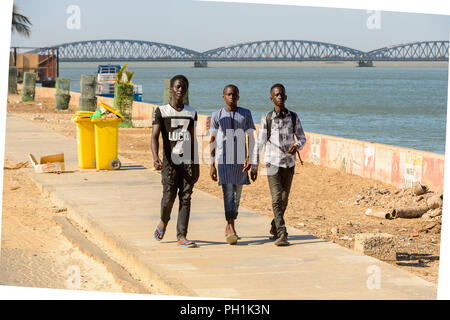 SAINT LOUIS, SENEGAL - Apr 24, 2017: Senegalesi non identificato tre ragazzi a piedi lungo la strada sulle rive dell'oceano a Saint Louis, uno dei bigge Foto Stock