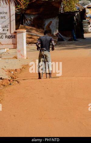 LAC ROSE reg., SENEGAL - Apr 26, 2017: Non identificato ragazzo senegalese corse in bicicletta in un villaggio. Foto Stock