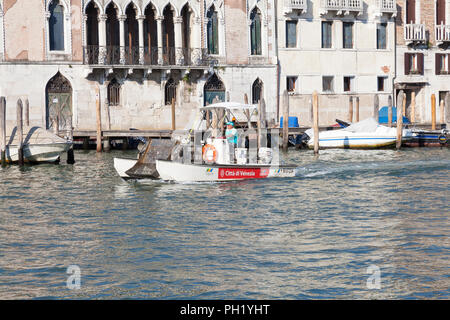 Un piccolo sVeritas kimmer barca per la raccolta di rifiuti galleggianti e rifiuti in plastica sul Grand Canal, Venezia, Veneto, Italia Foto Stock