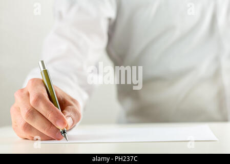 Close up della mano di un uomo di scrivere con una penna stilografica su un foglio bianco di carta bianca o un documento in un'immagine concettuale. Foto Stock