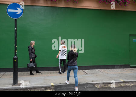 Parete Verde e una freccia plus i passanti in una strada di Londra a Soho, Londra Foto Stock