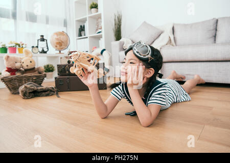 Kid giacente sul suo ventre e playiing con il suo giocattolo. lei sembra un po' annoiati di bit. Foto Stock