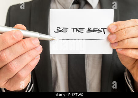 Vista dettagliata del terapeuta personale che mostra una carta bianca con un essere il miglior segno che vi incoraggia a vivere fino al vostro potenziale e realizzare i vostri obiettivi Foto Stock