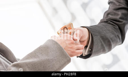 Close up imprenditore con handshake di denaro con il suo partner commerciale all'interno dell'Ufficio. Foto Stock