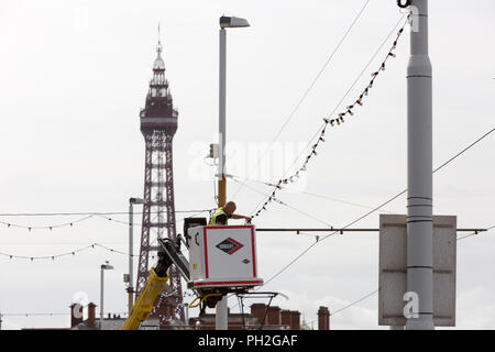 Blackpool , in Inghilterra. Xx Agosto , 2018. Tempo soleggiato oggi in Blackpool come alla fine della scorsa settimana di vacanze scolastiche estive si avvicina. Un operaio controlla uno degli oltre 1 milioni di bulbi precedendo le luminarie accendere domani. Credito: Chris Bull/Alamy Live News Foto Stock