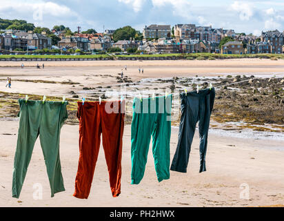 North Berwick, East Lothian, Scozia, Regno Unito, 30 agosto 2018. Tempo nel Regno Unito: Una giornata calda e soleggiata alla fine dell'estate nella città balneare di North Berwick. Pantaloni colorati che si stendono ad asciugare su una linea di lavaggio sulla spiaggia di West Bay a bassa marea Foto Stock