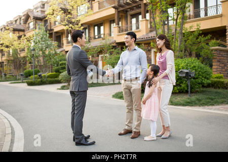 Felice famiglia giovane stringono le mani con agente immobiliare Foto Stock