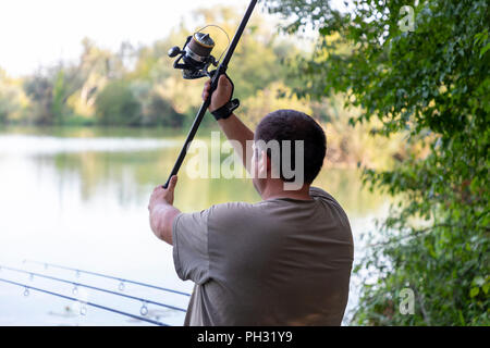 Pescatore in un lago carp fishing azione Foto Stock