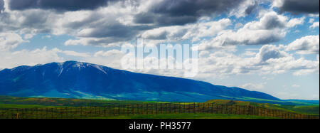 Vista panoramica del Wyoming infausto cieli nuvolosi su campi aperti e sezioni di Laramie Mountain Range, visto dalla strada statale 80 Foto Stock