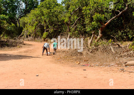 Strada di BISSAU GUINEA B. - 1 Maggio 2017: locale non identificato l uomo e la donna a piedi accanto alla strada in un villaggio in Guinea Bissau. Ancora molte persone in Foto Stock