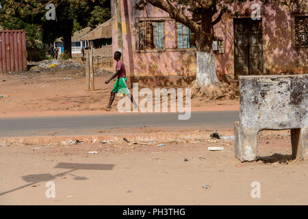 Strada di BISSAU GUINEA B. - 1 Maggio 2017: locale non identificato uomo cammina accanto alla strada in un villaggio in Guinea Bissau. Ancora molte persone nel paese Foto Stock