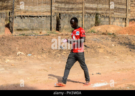 Strada di BISSAU GUINEA B. - 1 Maggio 2017: locale non identificato uomo cammina lungo la strada in un villaggio in Guinea Bissau. Ancora molte persone nel paese Foto Stock