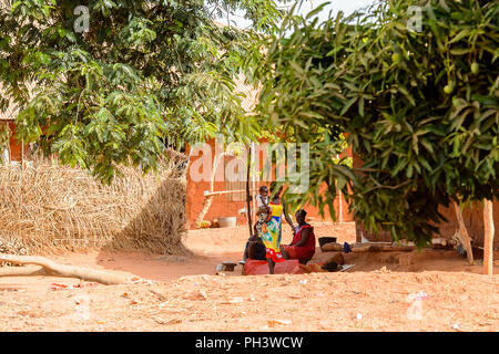 Strada di BISSAU GUINEA B. - 1 Maggio 2017: Unidentified donna locale porta una bambina in un villaggio in Guinea Bissau. Ancora molte persone nel paese Foto Stock