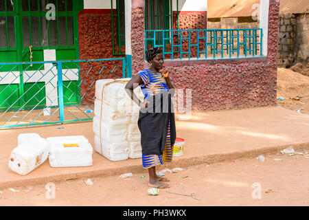Strada di BISSAU GUINEA B. - 1 Maggio 2017: locale non identificato donna in abiti tradizionali si erge accanto alla strada in un villaggio in Guinea Bissau. Ancora m Foto Stock