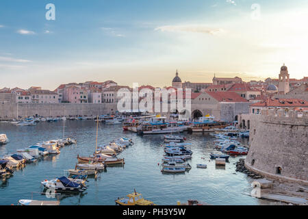 La vista della città vecchia di Dubrovnik in Croazia visto dal di fuori delle mura con il porto pieno di barche durante una splendente crepuscolo Foto Stock