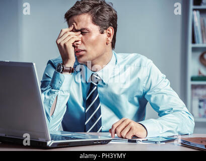 Ufficio giovane uomo con il dolore nella sua testa o un occhio. Foto di un uomo che soffrono di stress o di un mal di testa smorfie nel dolore. Il concetto di business Foto Stock