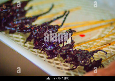 Produttore tailandese è la vendita di scorpione arrosto su strada a Bangkok il mercato notturno, Thailandia. Foto Stock