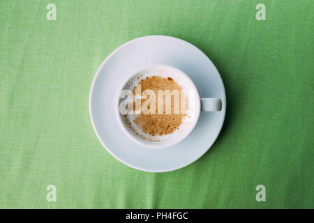 Bianco di ceramica tazza di caffè sulla tovaglia verde. Foto Stock