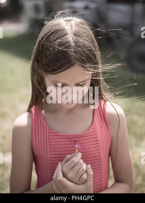 Ritratto di una bambina con un fiore rosa Foto Stock