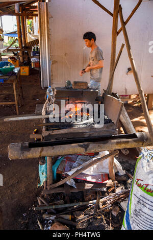 Rosso brillante di carbone caldo in una fucina di lavoro rendendo machete in Houayhe, un fabbri' village in Bolaven Plateau, provincia di Champasak, Laos, SE Asia Foto Stock