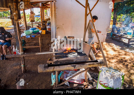 Rosso brillante di carbone caldo in una fucina di lavoro rendendo machete in Houayhe, un fabbri' village in Bolaven Plateau, provincia di Champasak, Laos, SE Asia Foto Stock