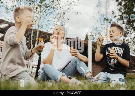 Close up della famiglia soffiare bolle all'aperto nel parco. Foto Stock