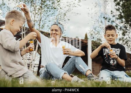 Close up della famiglia soffiare bolle all'aperto nel parco. Foto Stock