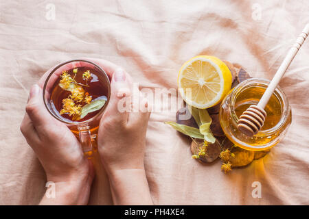 Tè con Linden, miele e limone. Il vassoio sul letto, il concetto di trattamento di raffreddori. Foto Stock