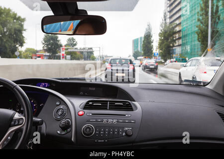 Alla guida di una autovettura in un ingorgo, vista dall'interno sulla strada affollata Foto Stock