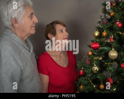 Ritratto orizzontale di una coppia di anziani la visione di un albero di Natale Foto Stock