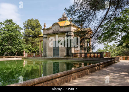 Ragazza in abito rosa è camminare vicino a padiglione neoclassico di Carlos IV e una piazza stagno nel labirinto di Horta Park. Foto Stock