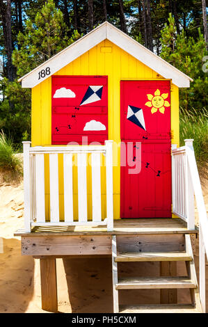 Un rosso e giallo beach hut sulla spiaggia Holkham, Norfolk Foto Stock