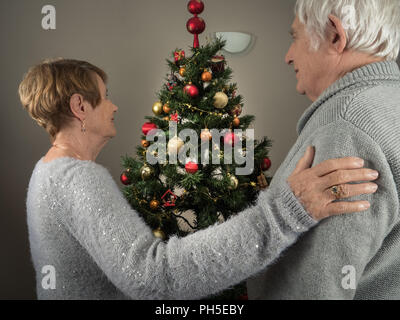 Ritratto orizzontale di una coppia di anziani la visione di un albero di Natale a casa Foto Stock