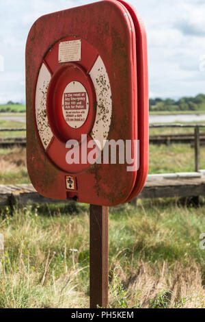 Close up di emergenza anello di vita nel suo caso su un post lungo la riva del fiume del fiume Wyre nel Lancashire, Inghilterra, Regno Unito Foto Stock