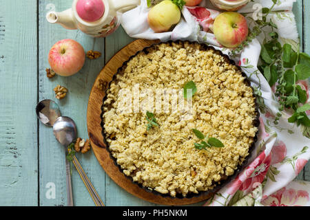 Cucina tradizionale inglese. Mele crumble, croccante in una teglia sul tavolo di legno. Vista superiore piatta sullo sfondo dei laici. Foto Stock