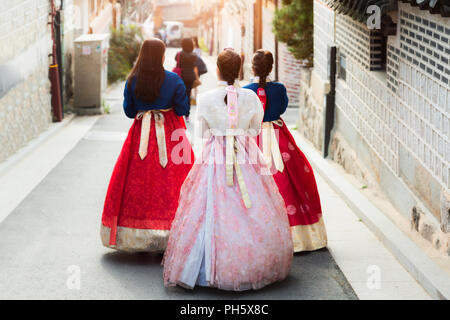 Indietro di tre donna che indossa hanbok camminando attraverso lo stile tradizionale delle case di il villaggio di Bukchon Hanok a Seul, in Corea del Sud. Foto Stock