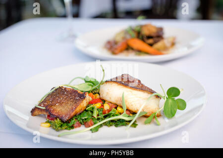 Arrosto di sable pesce con verdure a molla su una piastra bianca in un ristorante. Foto Stock