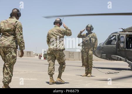 Stati Uniti Esercito aviatori, con la Task Force uragano, salutate U.S. Esercito il Mag. Gen. Walter Piatt, vice comandante della transizione della Combined Joint Task Force - Funzionamento inerenti risolvere, come egli assi un U.S. Esercito UH-60 Blackhawk dopo un breve a nord di Baghdad il comando delle operazioni presso il Camp Taji, Iraq, 18 giugno 2018. Attivato da successi accelerata contro ISIS nel 2017, le forze di coalizione il supporto ai nostri partner è in fase di evoluzione come possiamo assistere i nostri partner nel fornire sicurezza che consente gli sforzi di stabilizzazione. Foto Stock