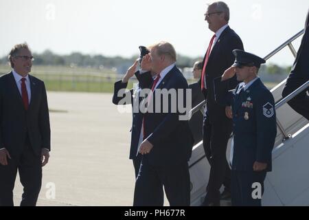 Stati Uniti Presidente Trump restituisce omaggio ai militari come egli è accolto da North Dakota governatore Doug Burgum, sinistra, al momento del suo arrivo presso la North Dakota Air National Guard Base, Fargo, N.D., 27 giugno 2018. Dal congressista Kevin Cramer è in arrivo con Trump. Foto Stock