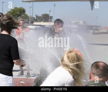 Col. John Klein, sessantesimo di mobilità in aria Wing Commander, riceve uno spruzzo di acqua dalla sua moglie e i suoi due figli dopo aver completato il suo "fini-volo" a Travis Air Force Base, California, 27 giugno 2018. Klein è stato il Wing Commander dal giugno 2016, e inizierà il suo nuovo incarico con il consiglio del Foreign Relations di New York. Foto Stock